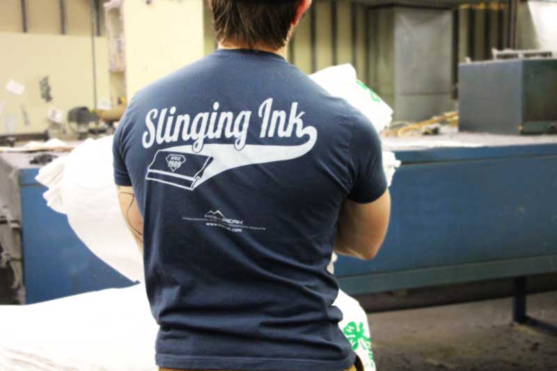 Employee holding a large stack of blank shirts