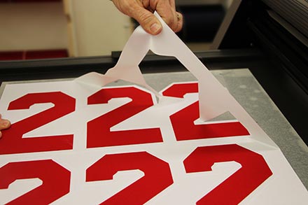Girl peeling vinyl letters from sheet
